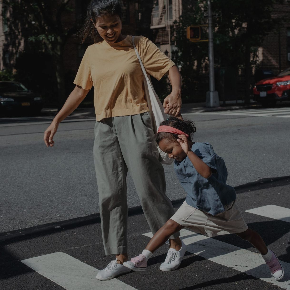 A mother and child crossing a city street